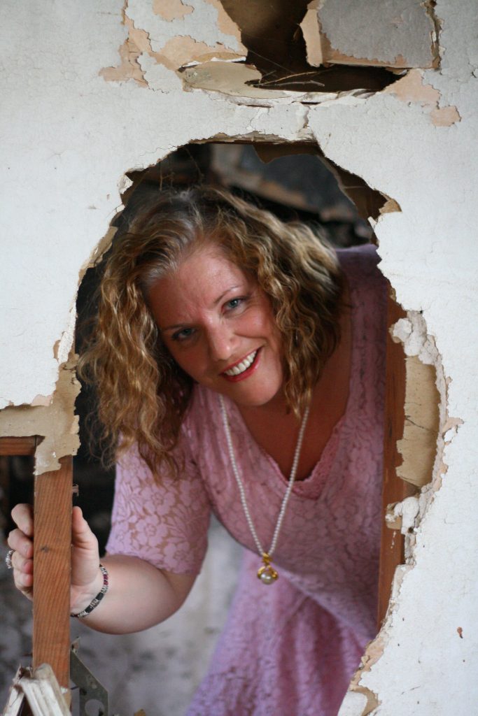 Woman (Julie Jordan Scott Julie JordanScott) seeming to burst through a broken wall on an abandoned home.