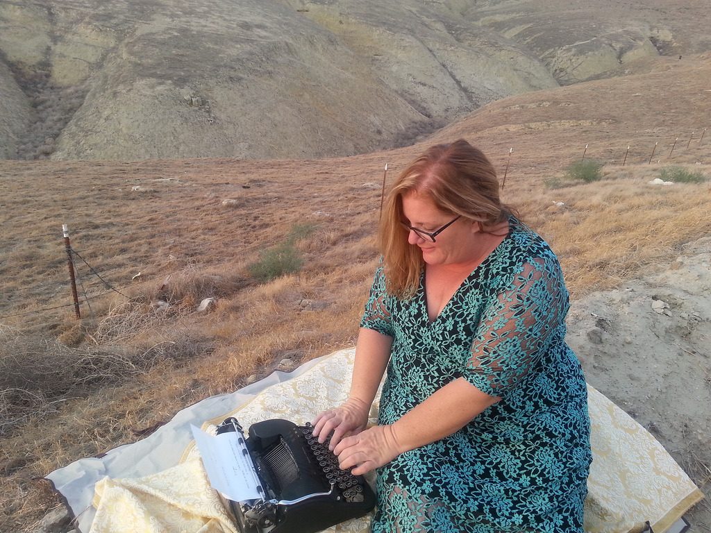 A women is typing in the countryside, another way of looking at a remnant of time and words, launching inspiration into the air.