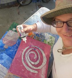 woman in a hiking hat creating mixed media art. 