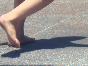 barefoot child at play in the playground, enjoying his shadow. Children don't see the shadow as a bad thing, but as a good thing.